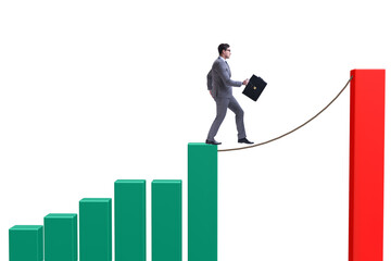 Businessman walking on tight rope between bar chart