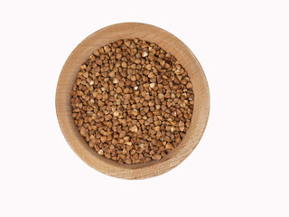 Raw buckwheat in wooden bowl on isolated white background