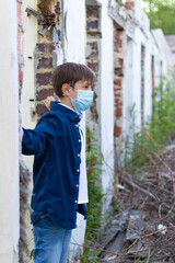 A fashionably dressed guy in a blue shirt stands against the background of an old destroyed brick wall. Close-up. Selective focus. Portrait