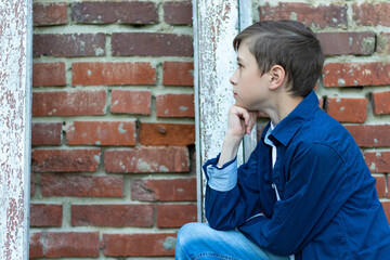 A fashionably dressed guy in a blue shirt stands by an old weathered door against a brick wall. Close-up. Selective focus. Portrait