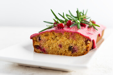 Cake with cranberries and rosemary on a white plate.