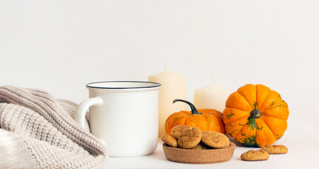Morning coffee, autumn atmosphere. Mug, scarf, cookies, pumpkins and candles on a white table