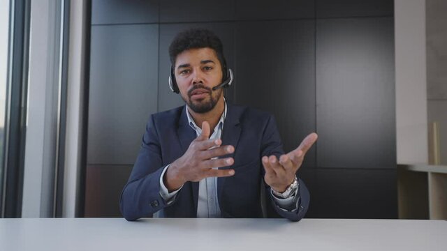 Min adult bearded man wearing headset and speaking to camera. Answering questions during online education training.