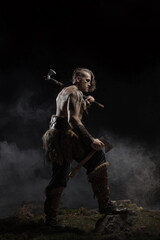 Fototapeta na wymiar Viking warrior in full with ax aggressively attacks on dark background