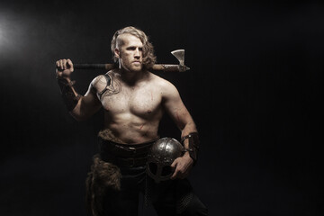 Viking warrior in full with ax aggressively attacks on dark background