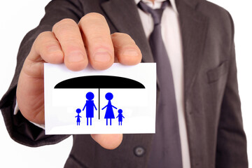 Concept d'assurance-vie avec un homme tenant une carte sur laquelle est dessiné une famille protégée par un parapluie