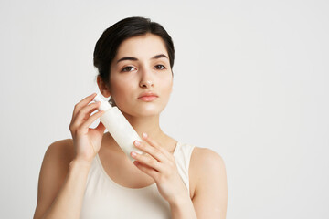 brunette in white tank top cream jar moisturizing health care