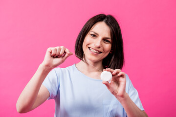 Beautiful young woman use dental floss on pink background