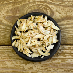 Dried garlic flakes on black plate close up flat lay photo on grey textured wooden background