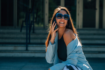 woman with long hair and sunglasses talking on mobile phone against backlight