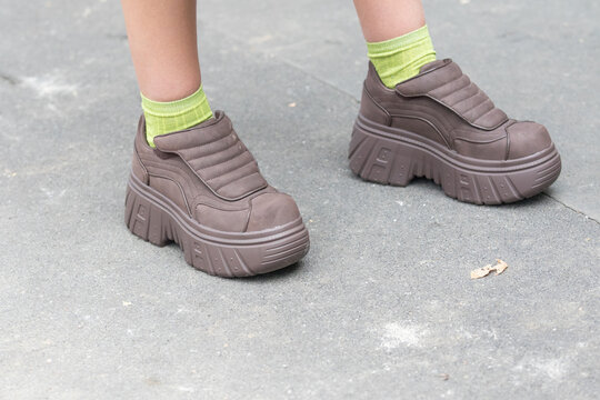 September 21, 2021: model wears brown wedge shoes and acid green stockings