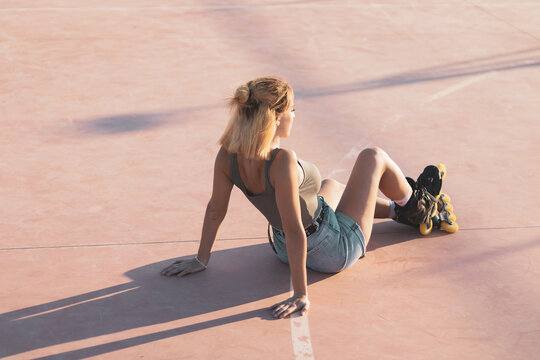 a very pretty girl riding on in-line skates on a basketball court.