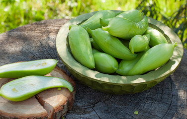 Achocha, Cyclanthera pedata. Mix of chilli. Healthy vegetables in wooden bowl on wooden log