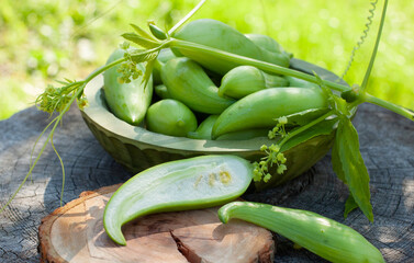 Achocha, Cyclanthera pedata. Mix of chilli. Healthy vegetables in wooden bowl on wooden log