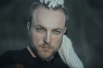 Close-up portrait of a young man with interesting depicts a viking staring at the camera