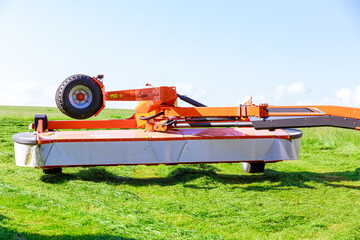 A red rotary mower cut the grass in the field. Clear field.