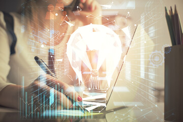 Double exposure of woman hands typing on computer and light bulb drawing. Idea concept.