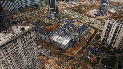 Construction of modern multi-storey buildings. Construction of a new city block. Buildings under construction and tower cranes. Aerial photography in cloudy weather.