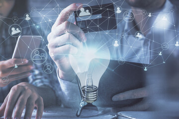 Double exposure of man and woman on-line shopping holding a credit card and light bulb hologram drawing. Idea concept.