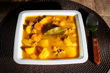 Potato stew with beef and carrot on a square plate.