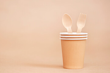 Fototapeta na wymiar Disposable paper cups with wooden fork and spoon on paper background. Environmentally friendly concept.