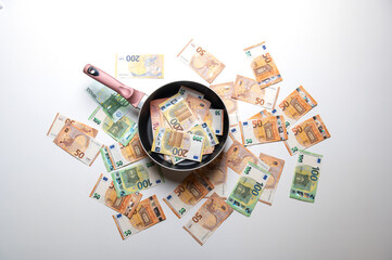 New frying pan with money euro banknotes on a white background.