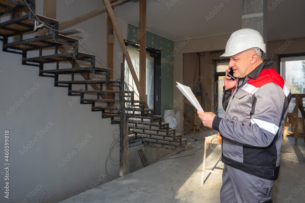 Poster construction engineer with a phone in his hands. man at construction site. engineer is talking to cu