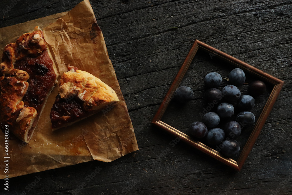 Poster top view of a sliced pie on a baking paper and some blueberries in a wooden, square frame