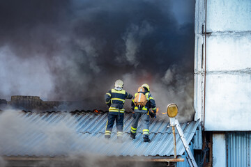 firefighters are standing on roof. Firefighters view from afar. Two employees of fire department....