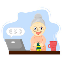 A happy grandmother at a table with a laptop is taking a knitting master class