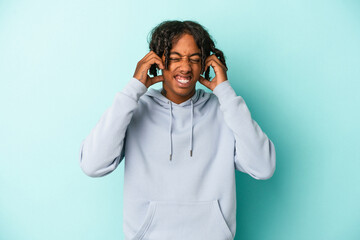 Young african american man isolated on blue background covering ears with hands.