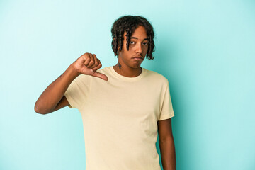 Young african american man isolated on blue background showing a dislike gesture, thumbs down....