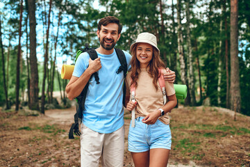 A loving couple of hikers stand with backpacks on the background of the forest. Camping, travel, hiking.