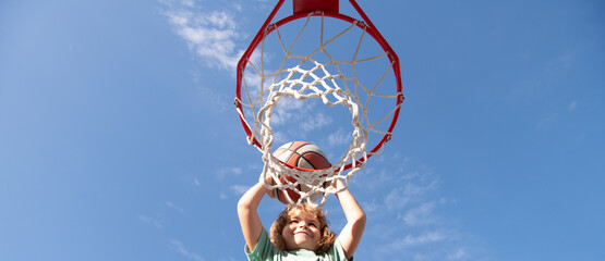 Kid boy playing basketball, banner with copy space. Child playing basketball outdoors shooting slam...