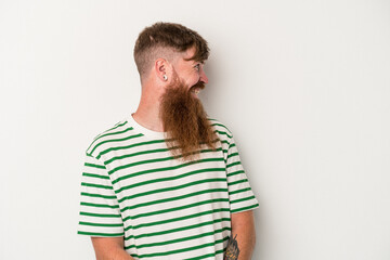 Young caucasian ginger man with long beard isolated on white background looks aside smiling, cheerful and pleasant.