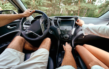 Young couple in a new car. A man driving a car with his girlfriend and having fun. Buying and...