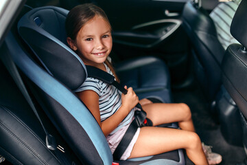 Child cute girl in a car seat is protected by seat belts. Leisure, travel, tourism. Protection...