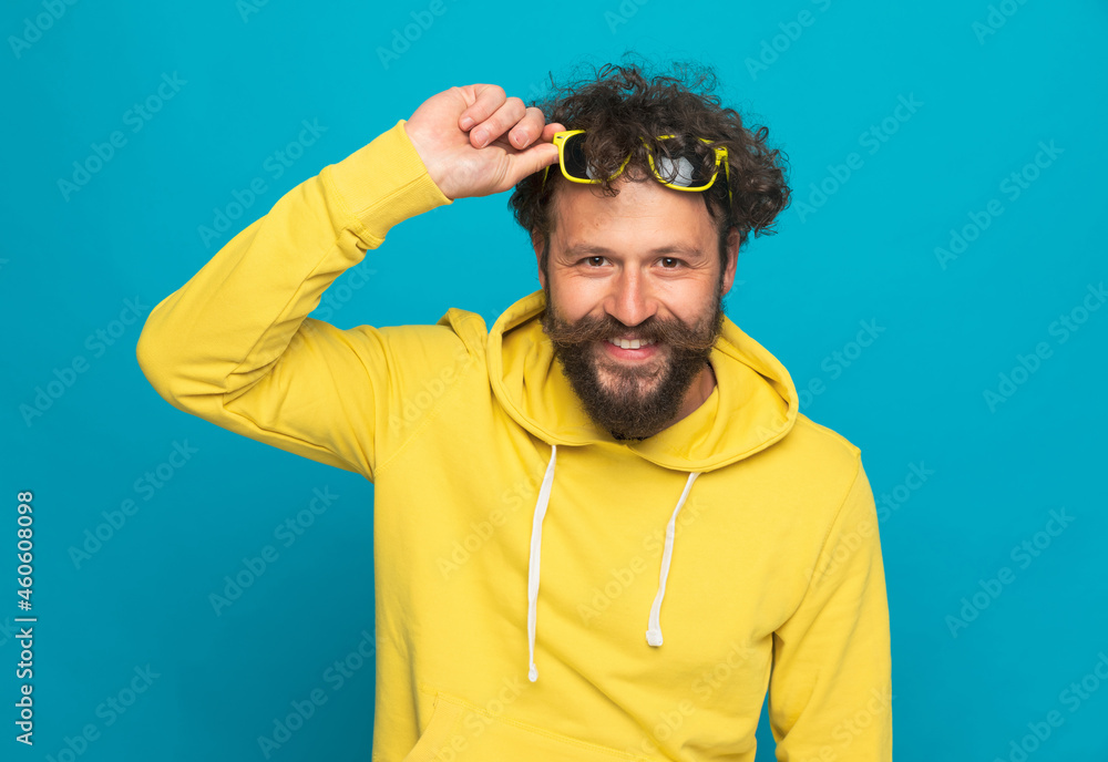 Sticker handsome young guy in yellow hoodie holding glasses on forehead