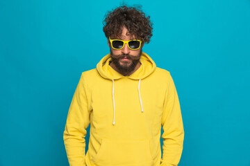 bearded casual man wearing yellow hoodie and sunglasses confidently posing
