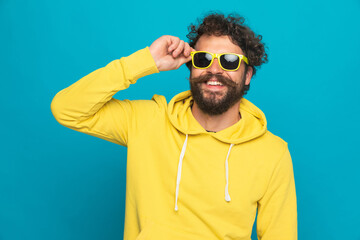 happy casual man with moustache fixing sunglasses and smiling
