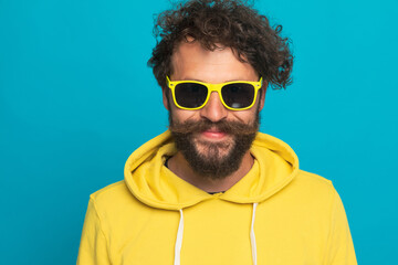 curly hair guy in yellow sweatshirt with glasses smiling and posing