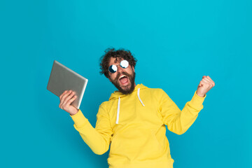 excited bearded man holding tab, screaming and celebrating victory