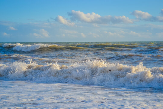 Small storm at sunset, high waves with white foam