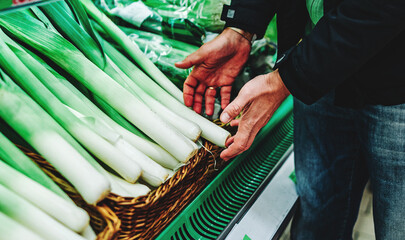 man hand holding leek in grocery store in supermarket