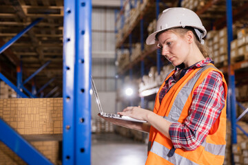 Woman worker using computer laptop working checking stock in warehouse, Logistic concept