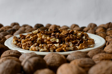 A plate full of walnut kernels surrounded by walnuts
