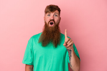 Young caucasian ginger man with long beard isolated on pink background having an idea, inspiration concept.