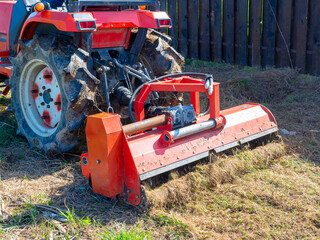 close-up of a tractor with a chain mower chopping dry grass. Maintenance of the territory, mulching...