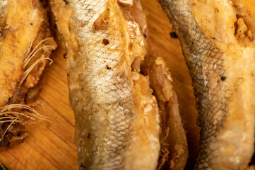 Small fried fish on a wooden board, close-up, selective focus.