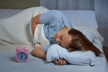 Senior woman in blue pajamas slept through time, she suffers from insomnia
